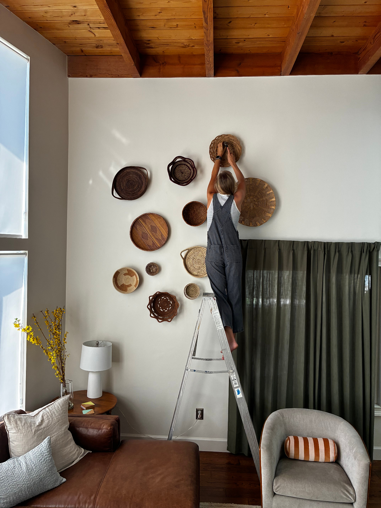 Anne hanging woven baskets on a living room wall